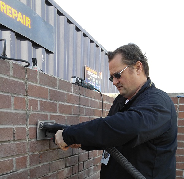 Steven Tersh of the Robert Bosch Tool Corp. demonstrates a mortar cutting tool with vacuum attachment.