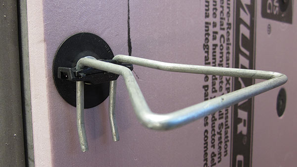 Single-barrel veneer anchor with a thermal clip and brick-tie washer to secure the insulation and prevent thermal bridging.