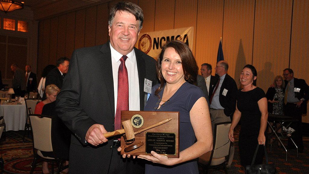 NCMCA 2015 president Ashlee Moore passes the gavel, and thus the presidency, to Bob Gates.