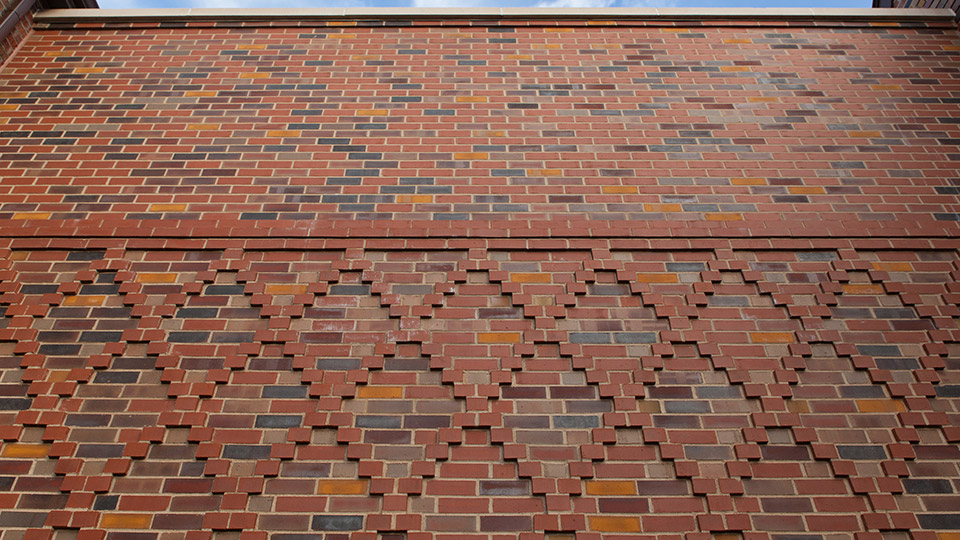 The diamond pattern on the new brick wall linking the two houses of the new student center matches an original pattern on one building’s façade.